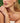Close-up of a woman wearing a necklace, bracelet, and earrings with a blurred green background